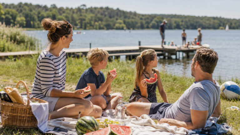 Familie picknickt am deutschen See im Sommer mit Wassermelone