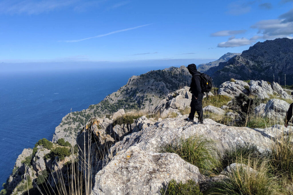 Wanderer auf einem Felsgrat der Serra de Tramuntana, unten das Meer